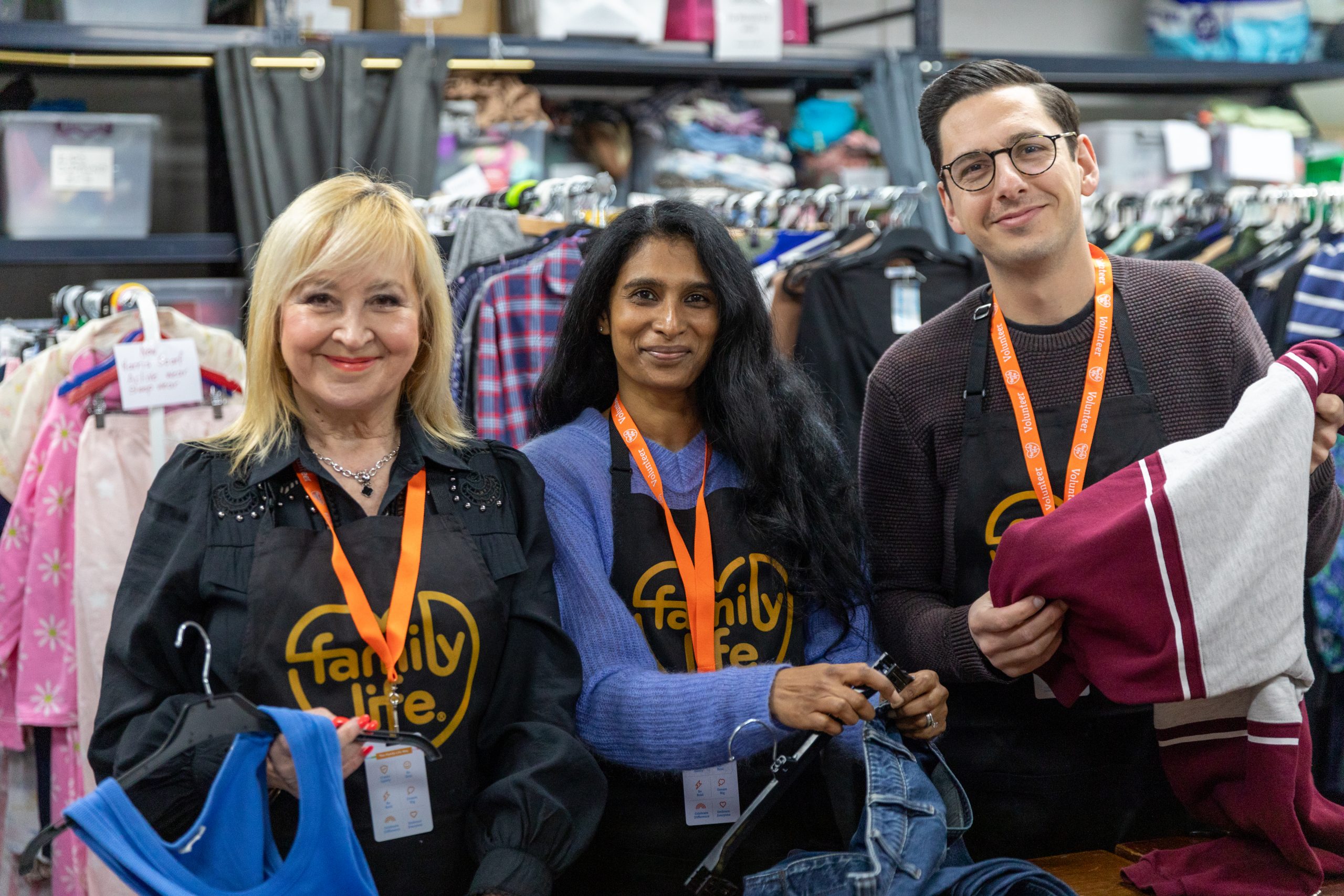 Three Famioly Life volunteers at a warehouse, sorting clothes